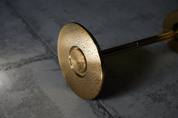 Goldener Lampenstandfuß mit strukturierter Oberfläche auf grauem Fliesenboden, modernes Design