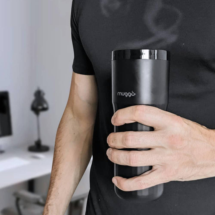 Mann hält schwarzen Muggo Thermobecher im modernen Büro