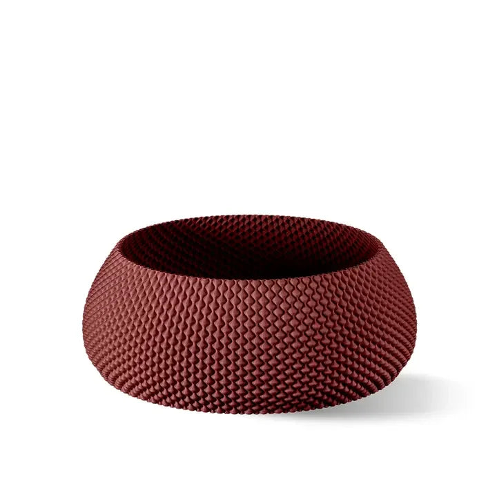 Eine strukturierte, runde Schale in Dunkelrot mit einem geometrischen Muster aus erhabenen Rauten auf der Oberfläche.
