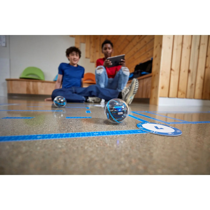 Zwei Kinder steuern Sphero Bolt Roboter mit Tablet auf Parcours im Klassenraum