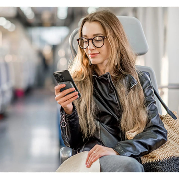 Frau mit Brille und Lederjacke nutzt Smartphone im Zug, moderner Reisekomfort