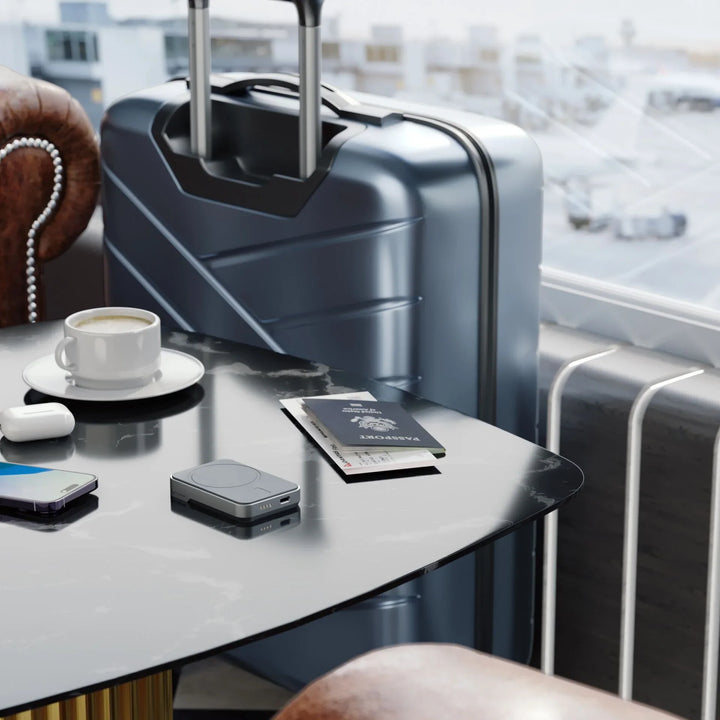 Alogic Matrix 3-in-1 Ladegerät, Reisepass, Handy und Koffer am Flughafentisch