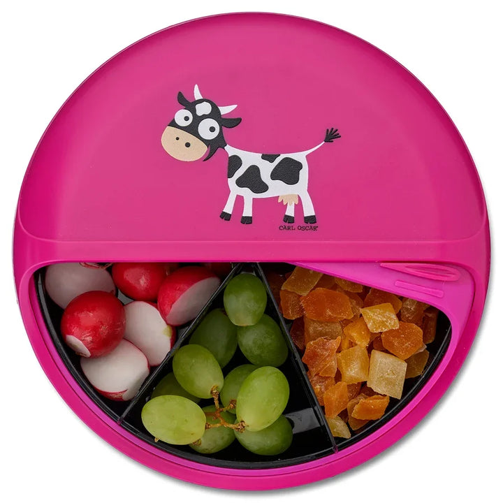 Lila Bento Box mit Kuhmotiv, gefüllt mit Radieschen, grünen Trauben und Trockenfrüchten