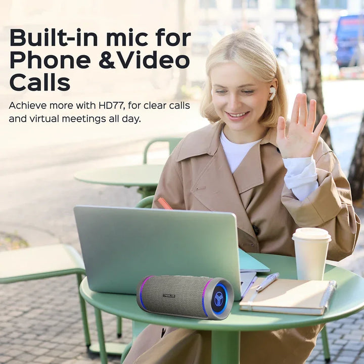 Frau mit Laptop, Bluetooth-Lautsprecher mit eingebautem Mikrofon bei Videokonferenz im Café