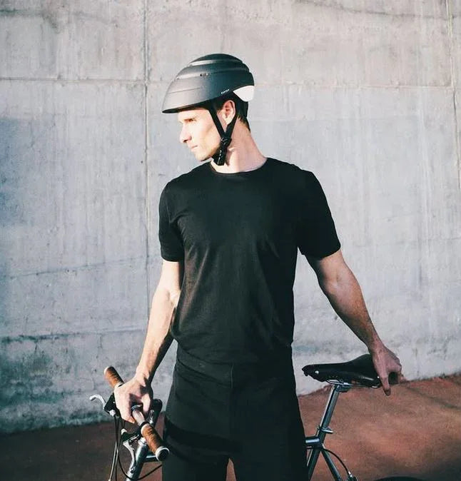 Mann mit schwarzem Fahrradhelm und Fahrrad vor Betonwand, urbanes Fahrradfahren