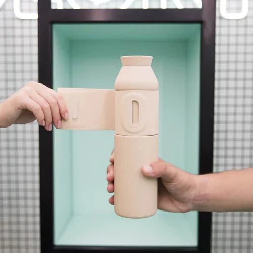 Beige Closca Trinkflasche aus Kunststoff, von zwei Händen vor mintgrünem Hintergrund gehalten.