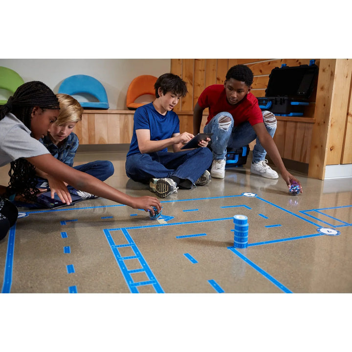 Kinder programmieren Roboter auf blauem Parcoursboden in moderner Lernumgebung