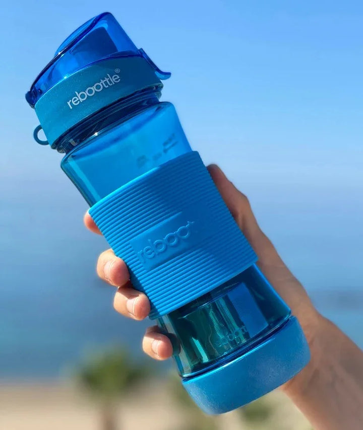 Blaue rebottle Trinkflasche aus Kunststoff, von Hand gehalten, vor blauem Hintergrund