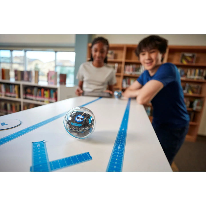 Kinder programmieren Sphero Roboter Kugel auf Lineal-Parcours in Schulbibliothek