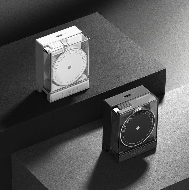 Zwei moderne Ladeboxen, eine weiße und eine schwarze, mit dem Text „GET YOUR GROOVE ON“, positioniert auf geometrischen schwarzen Oberflächen.