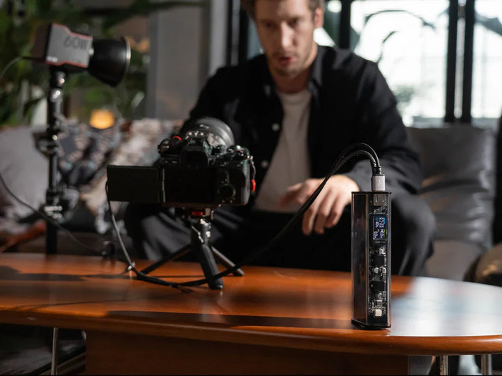 Ein Mann sitzt auf einem Sofa mit einer Kamera und einem Stativ.