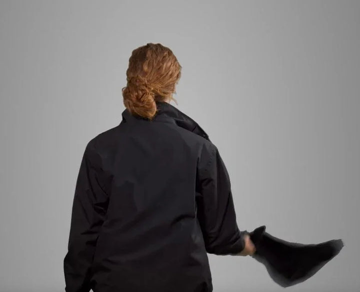 Person von hinten mit schwarzer Tech-Jacke entfernt Kapuze, neutraler Hintergrund